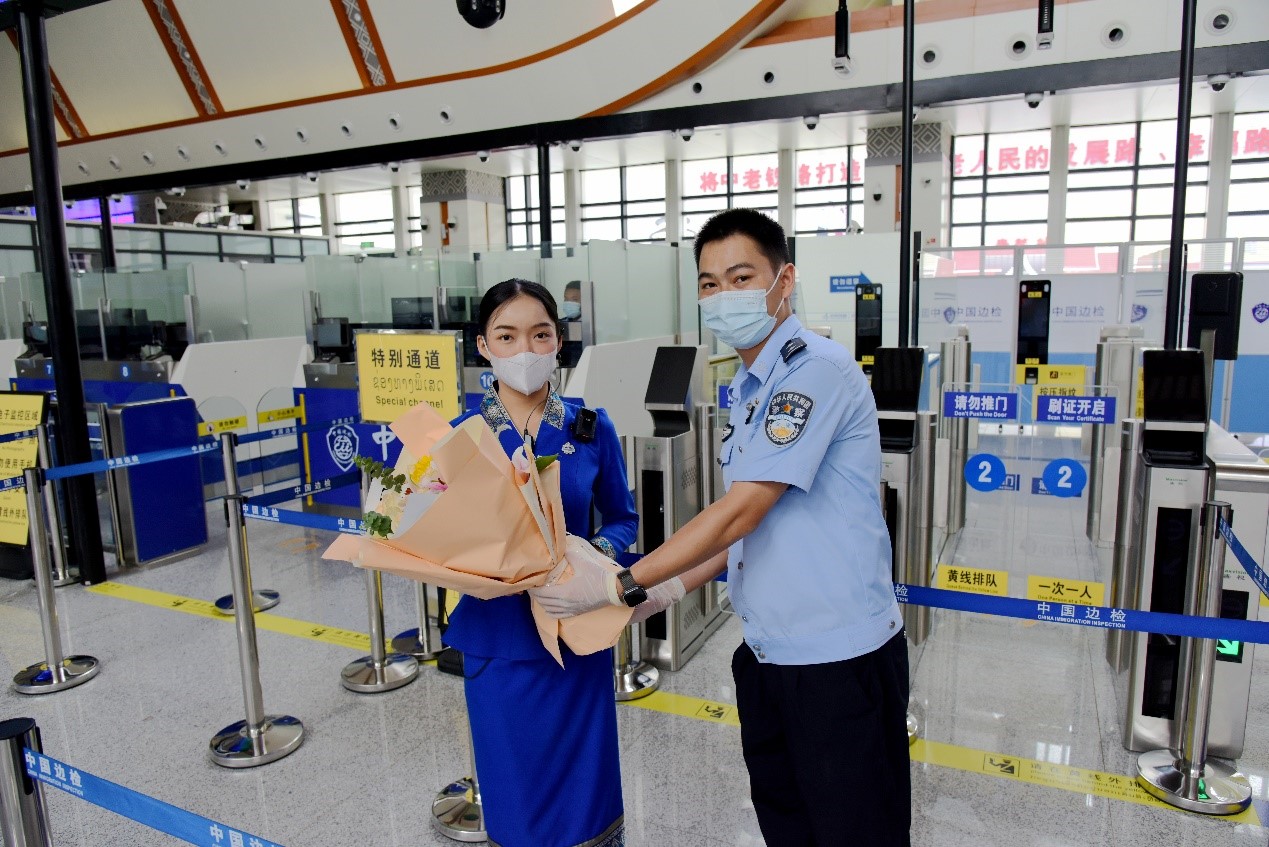 磨憨出入境邊防檢查站民警為中老鐵路第100萬名出入境旅客，D888次國際旅客列車老撾籍乘務員森達拉·妮緹婭（Sengdala Nitiya），送上鮮花。黃遠飛 攝