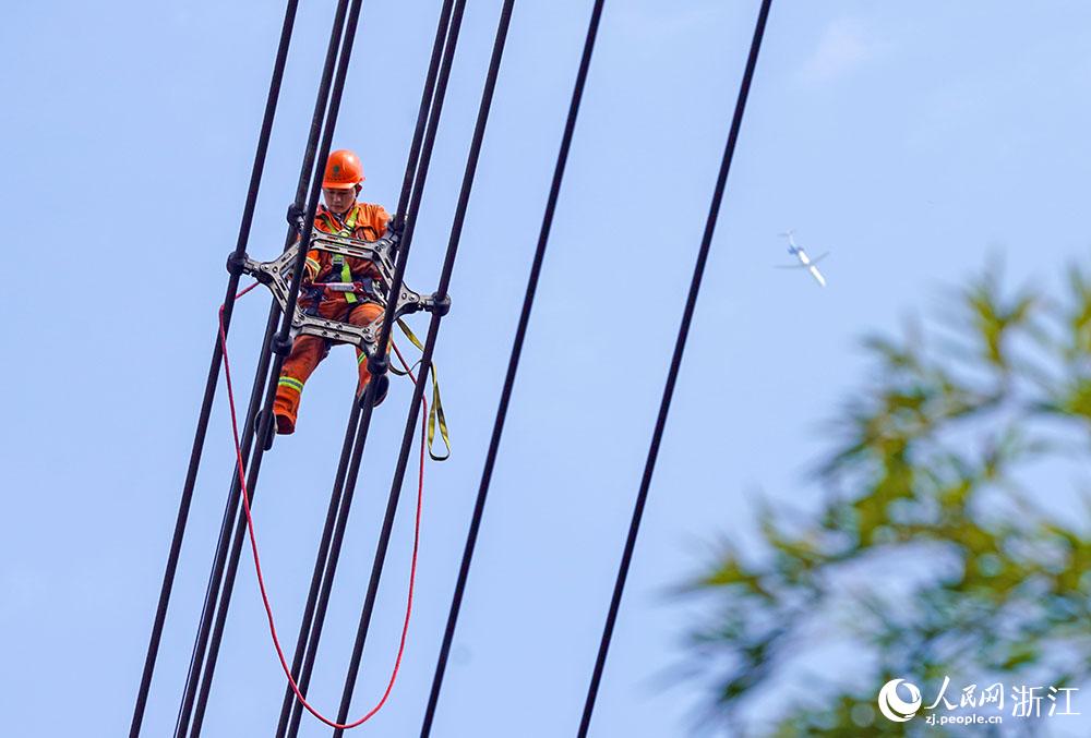 3月11日，在浙江省諸暨市河上鎮(zhèn)，浙江省送變電工程有限公司檢修人員在高空的導(dǎo)線上進(jìn)行線路檢修維護(hù)。人民網(wǎng) 章勇濤攝