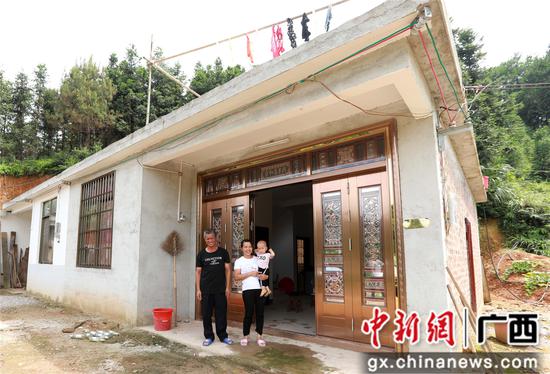 7月4日，在廣西柳州市融安縣大坡鄉(xiāng)崗偉村，脫貧戶肖裕安（左）與妻子、外孫在改造后的房屋前合影。覃慶和 攝