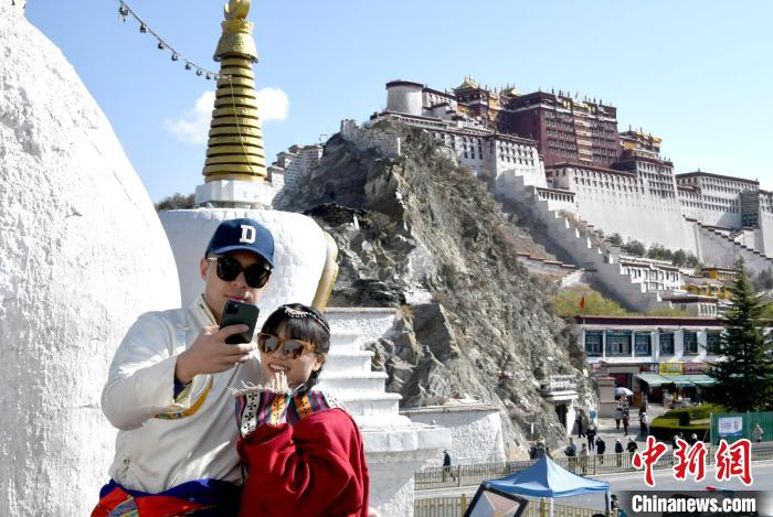 4月17日，游客身著藏式元素服裝在拉薩布達拉宮觀景臺拍照留念?！±盍?攝